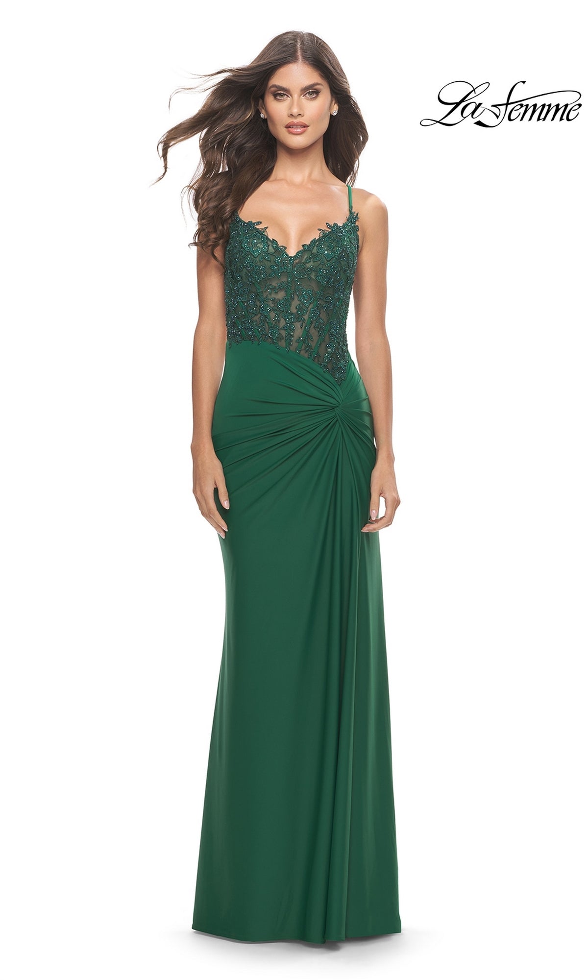 A woman in a La Femme Long Prom Dress 31520 in dark green, with a lace embroidered bodice, spaghetti straps, and ruched waist detail, stands against a white background.